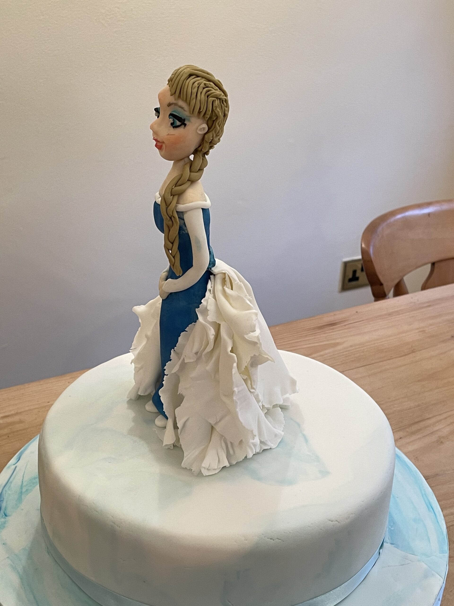 Picture provides an example of fondant character topper, Ella from Frozen.