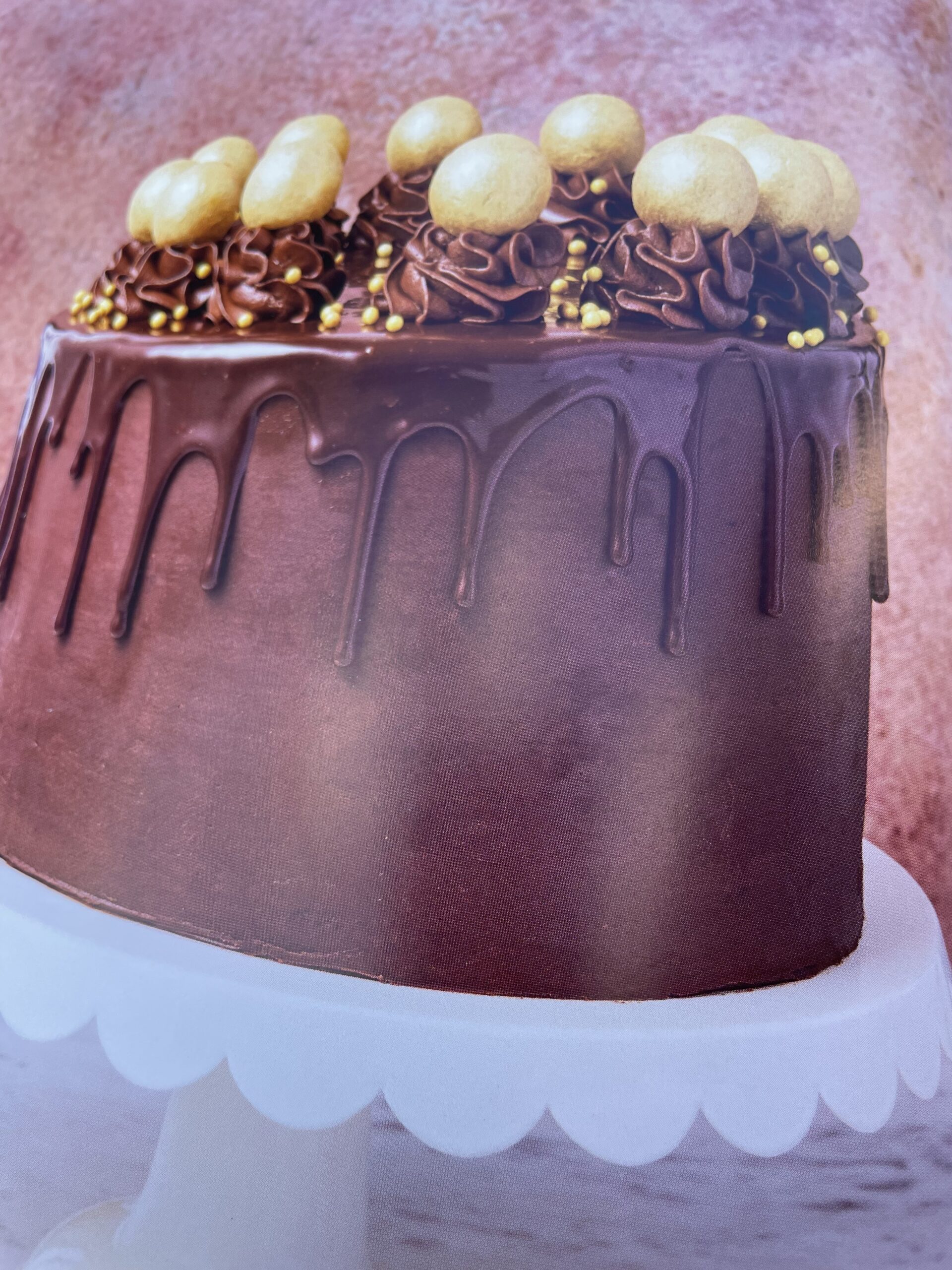 Picture depicts chocolate cake with choice of filling, decorated with chocolate ganache, contrasting chocolate drip and truffles.