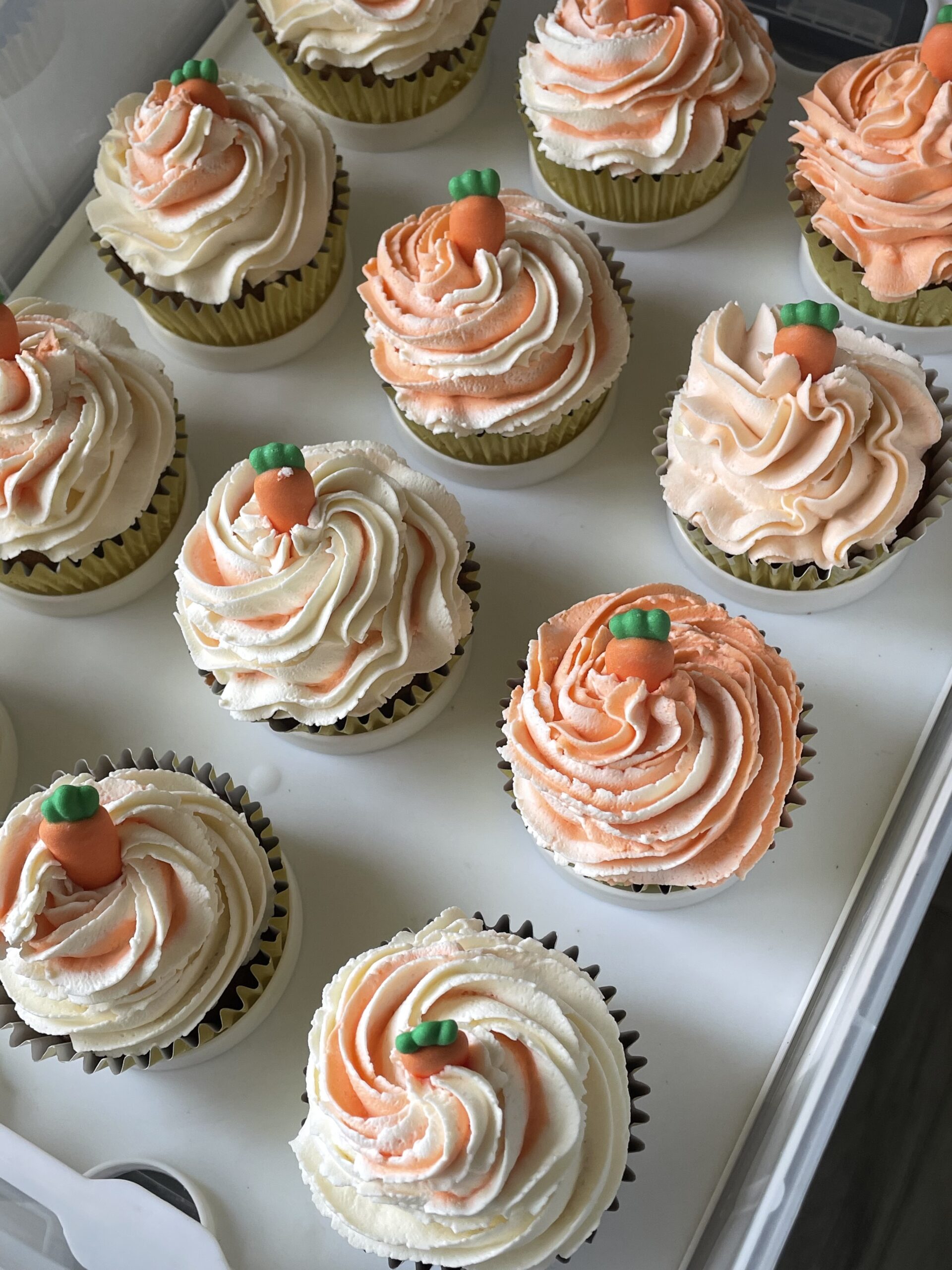 Photo of carrot cake cupcakes topped with two tone frosting.