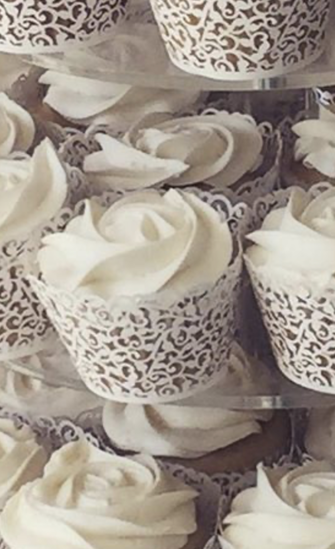 Picture of cupcakes with floral piped frosting, sat in decorative cupcake covers.