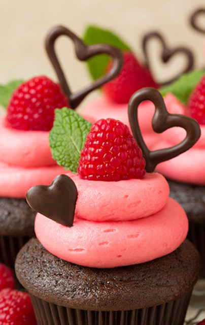 Photo of chocolate sponge cupcakes, strawberry frosting and fresh strawberry, completed with chocolate hearts